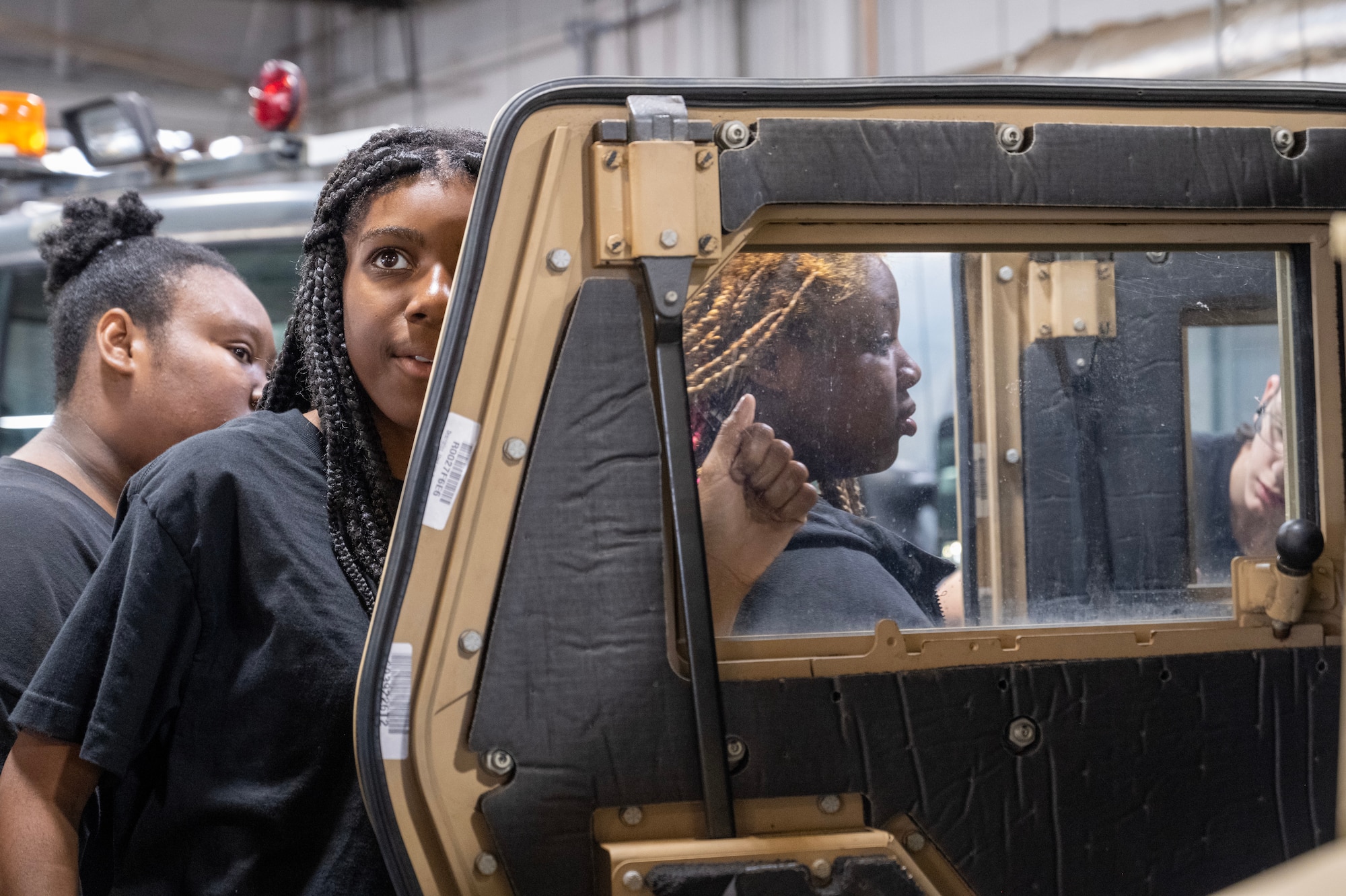A young woman knocks on a humvee door.