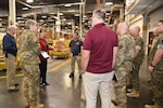 Photo is of a group of people standing in a large warehouse