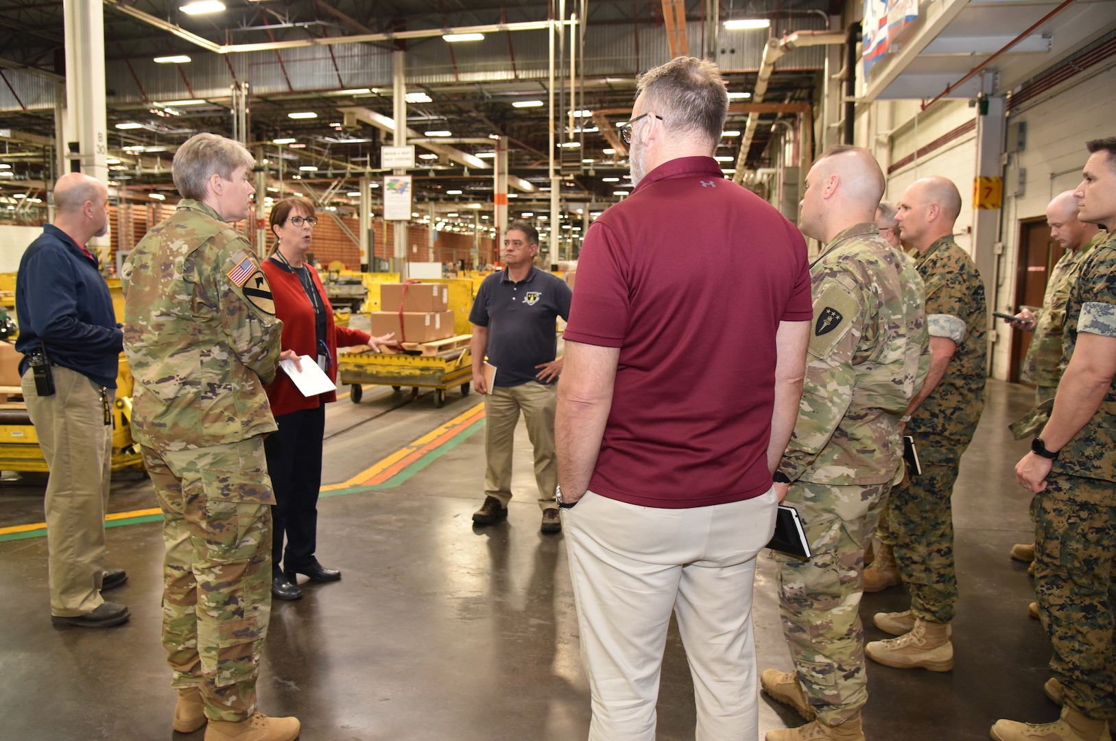 Photo is of a group of people standing in a large warehouse