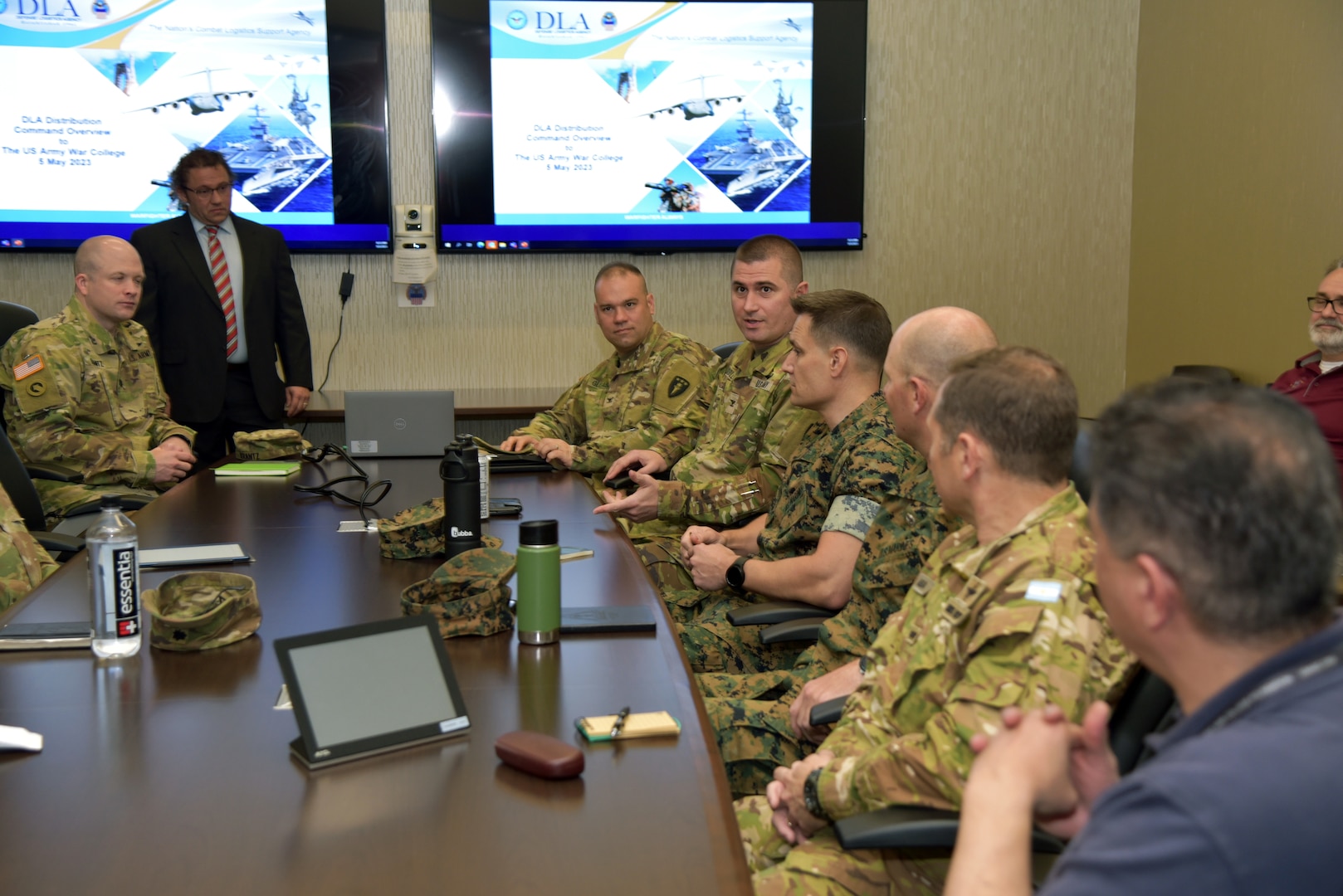 Photo is of people sitting in a conference room, one person is speaking.