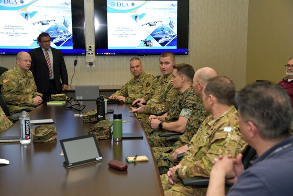 Photo is of people sitting in a conference room, one person is speaking.
