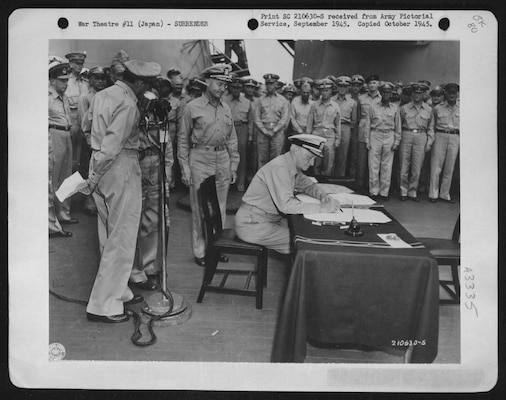 Fleet Admiral Chester W. Nimitz signs for the United States during the surrender ceremonies aboard USS Missouri in Tokyo Bay, ca. September 1945. At the microphone (left) is Army Gen. Douglas MacArthur. Image courtesy National Archives and Records Administration (342-FH-3A03335-117348AC)