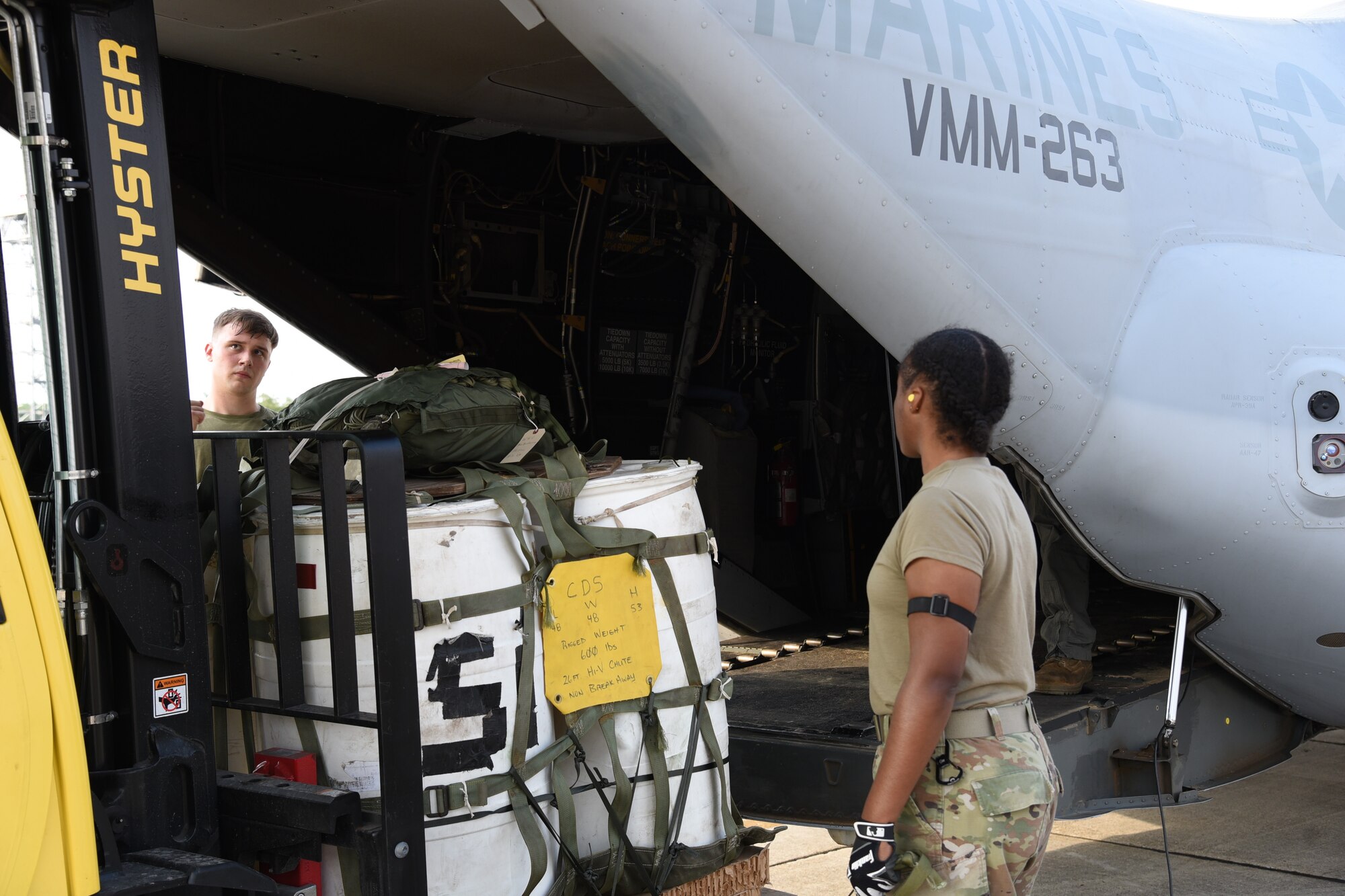 A Marine and an Airman work together to load a container delivery system on a MV-22B Osprey from the Marine Medium Tiltrotor Squadron (VMM) 263 to be dropped into the Camp Shelby drop zone.