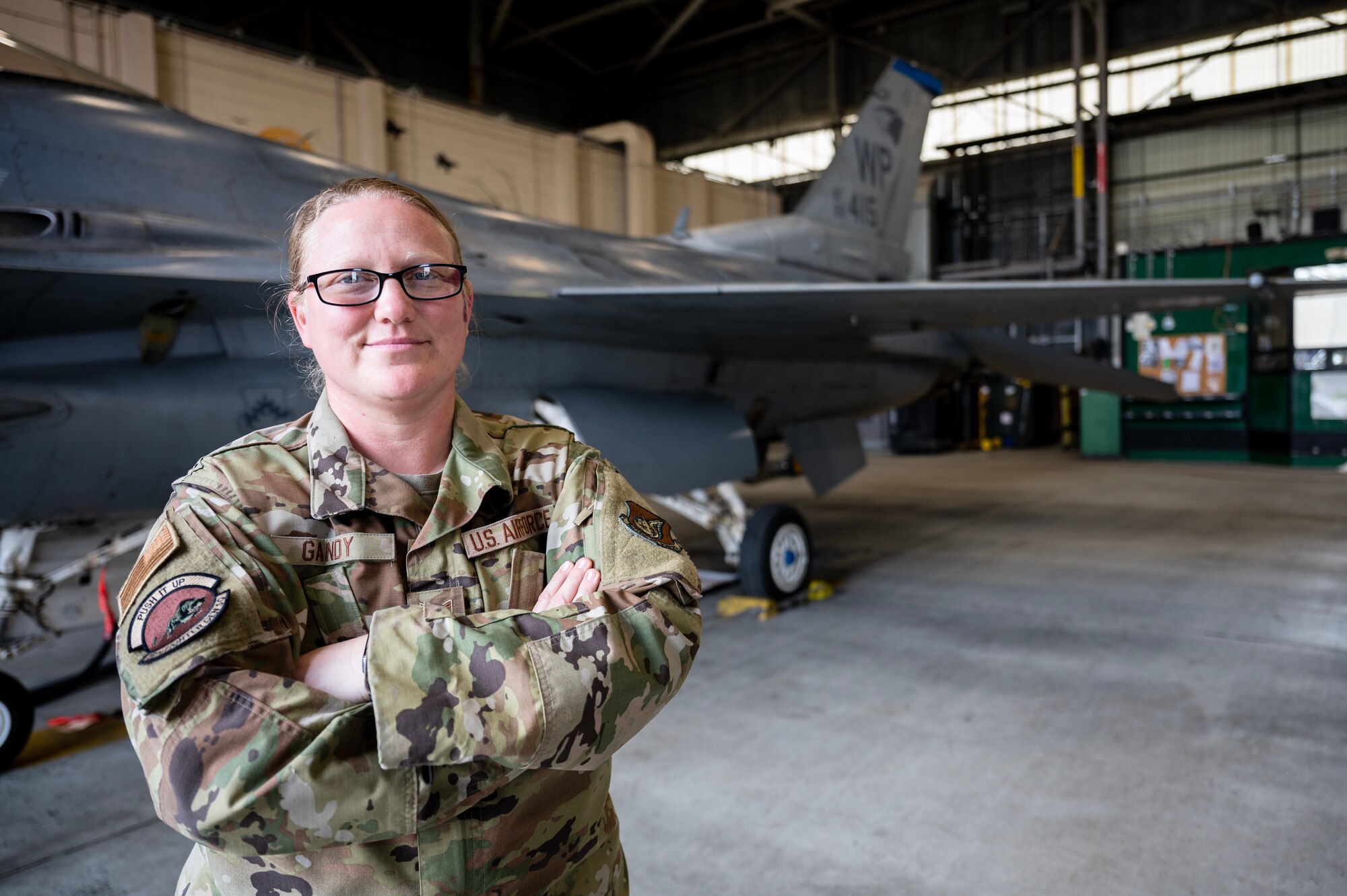 Tech. Sgt. Corrin Gandy stands in front of an F-16 Fighting Falcon at Kunsan Air Base