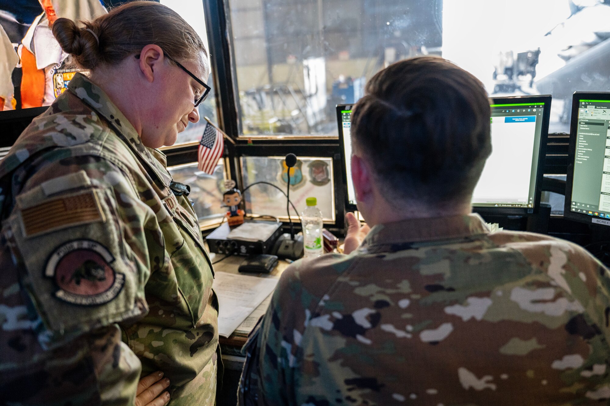 Tech. Sgt. Corrin Gandy coordinates with Staff Sgt. Andrew Kozak at a desk