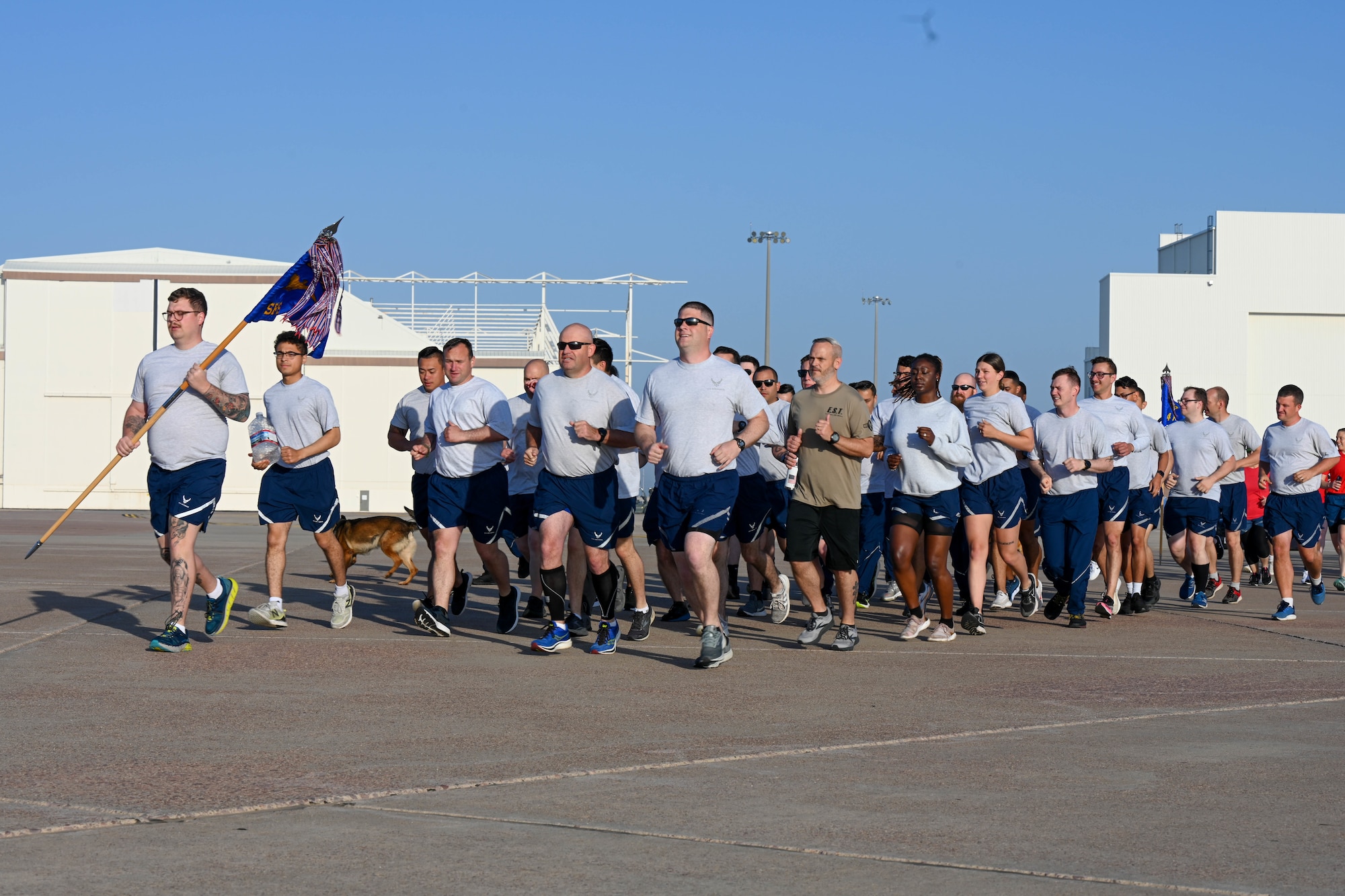 Airmen from the 97th Security Forces Squadron (SFS) run on the flight line at Altus Air Force Base, Oklahoma, May 12, 2023. 97th SFS military working dog handlers included their dogs in the wing run. (U.S. Air Force photo by Senior Airman Trenton Jancze)