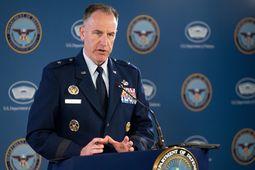 A man in uniform speaks behind a lectern.