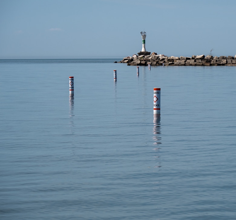 Buoys floating along the waters of Ashtabula Harbor towards the lighthouse marking the location of a submerged stone wall below.