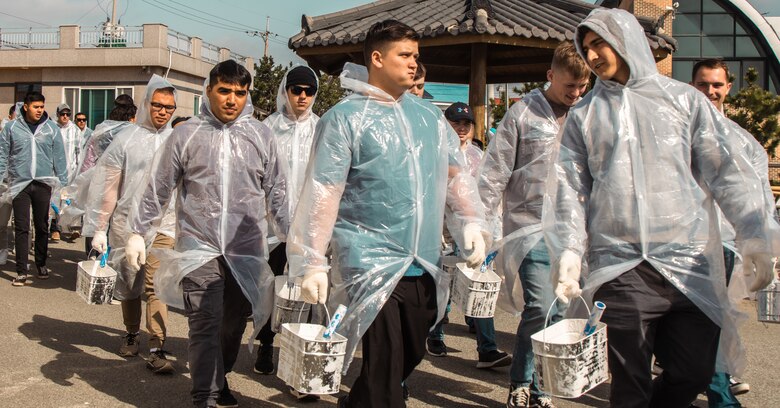 U.S. Marines and Navy Sailors walk to a house during a village restoration project at Damupo Village, South Korea, on March 25, 2023. On Aug. 29, 2022, Typhoon Hinnamnor overtook the village and severely damaged the structures. To help the village recover from the natural disaster, Marines and local residents came together to repaint the damaged homes. (U.S. Marine Corps photo by Lance Cpl. Jonathan Beauchamp)