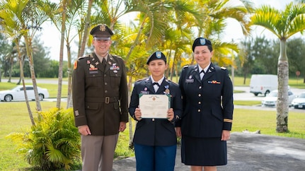 Spc. Kiana Siguenza, center, of SECFOR 6, Task Force Talon, 38th Air Defense Artillery Brigade, receives the Army Achievement Medal from Maj. Kyle Hermanson, Talon commander, left, and Capt. Denise Chargualaf, SECFOR commander, during a ceremony in Yigo, Guam May 5, 2023. Siguenza, who is a deployed member of the Guam National Guard, is the first recipient of the Expert Soldier Badge in the organization.