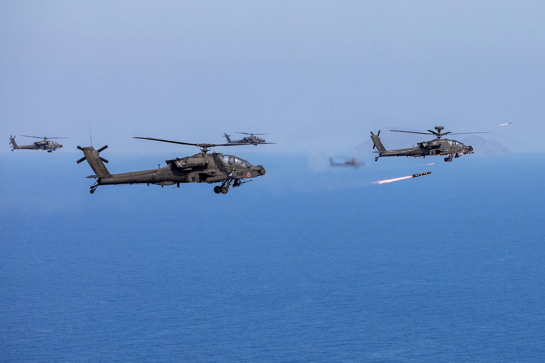 Helicopters fly close together while one fires a missile.