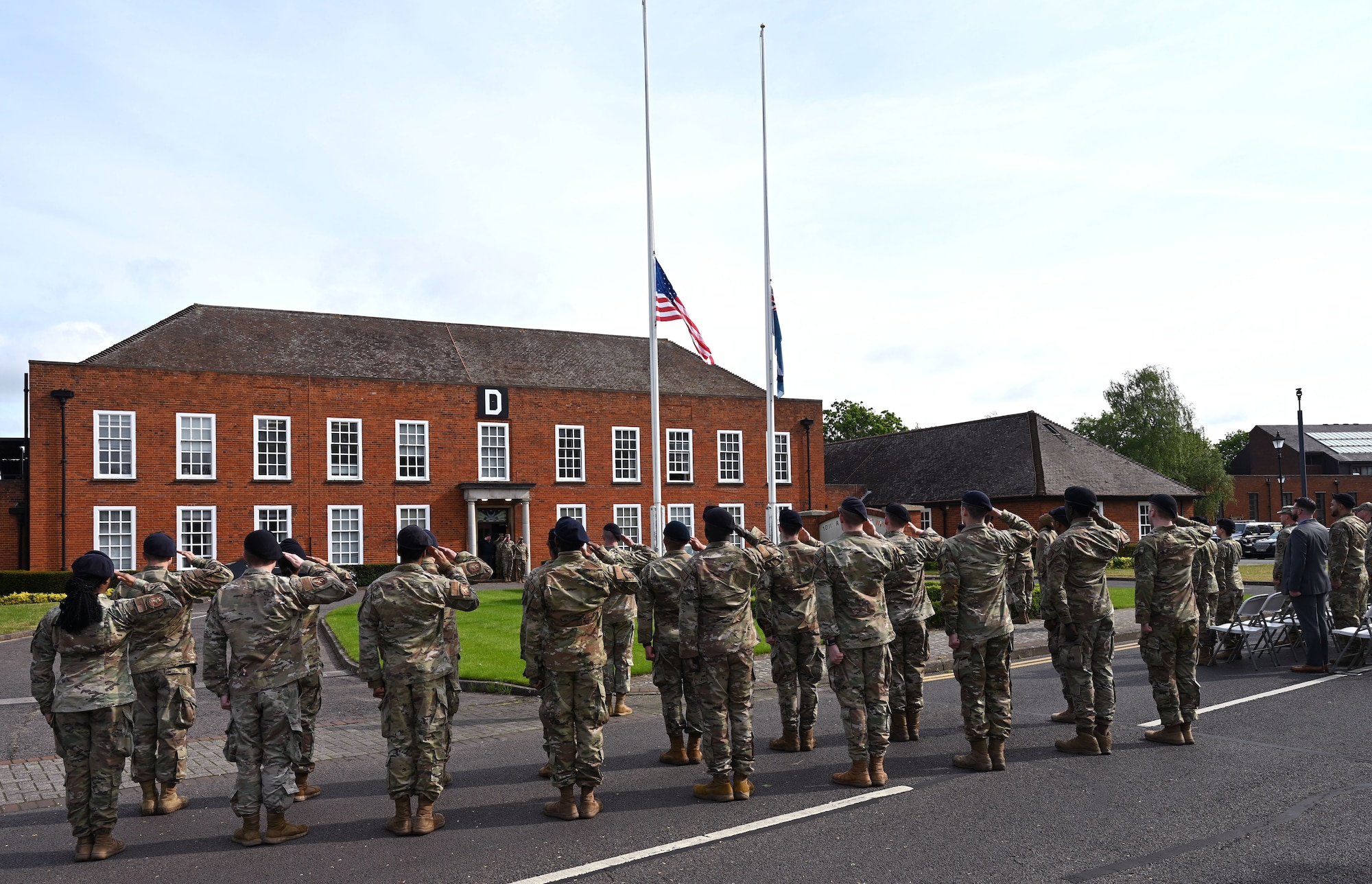 U.S. Air Force Defenders from the 100th Security Forces Squadron salute the Stars and Stripes while the National Anthem plays at the Police Week opening ceremony May 15, 2023, at Royal Air Force Mildenhall, England. Police Week is held every year in May and this year is May 15 to 19. (U.S. Air Force photo by Karen Abeyasekere)