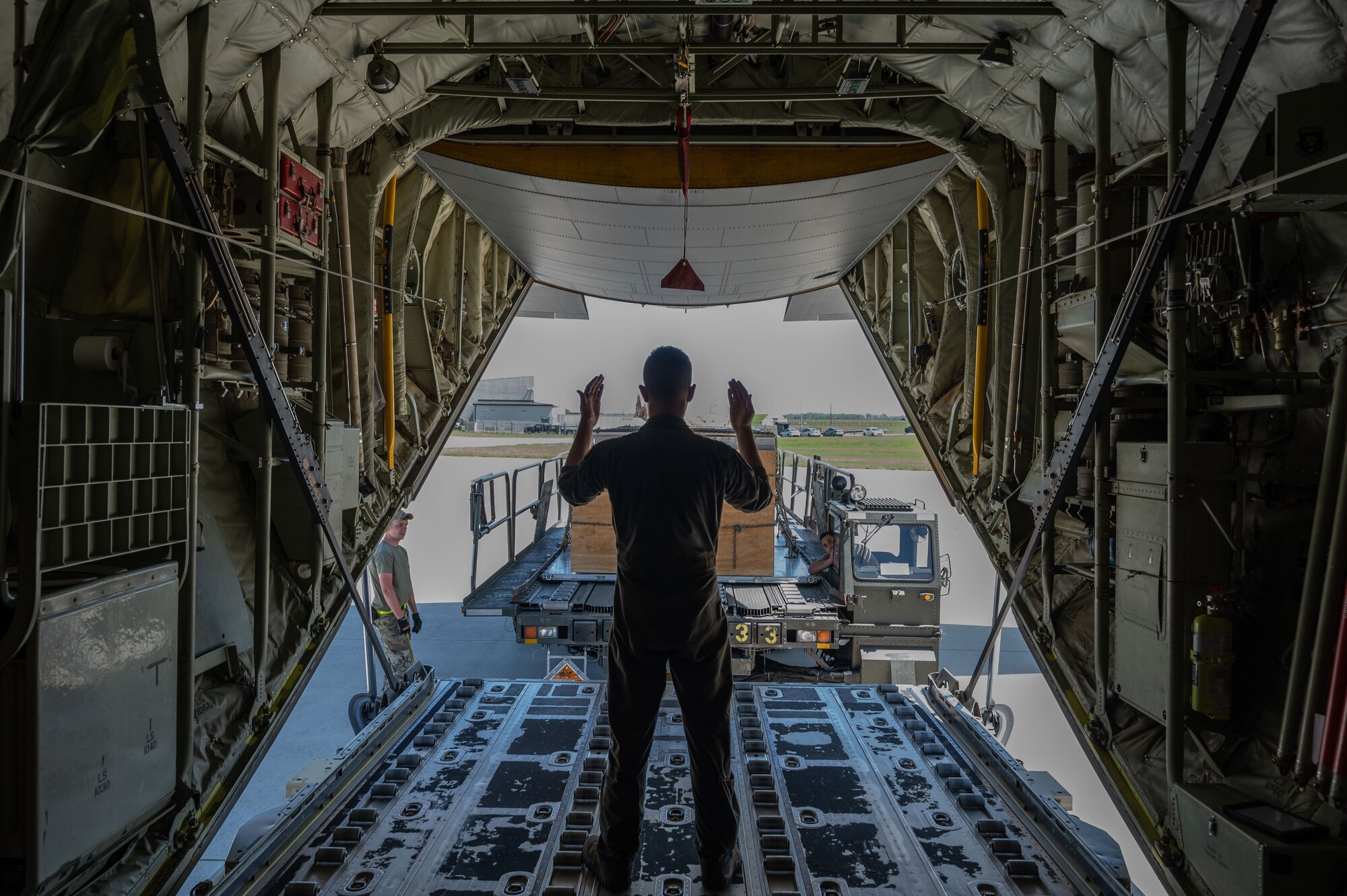 Senior Airman James Graves, 61st Airlift Squadron loadmaster, marshals cargo onto a C-130J Super Hercules, assigned to the 19th Airlift Wing at Little Rock Air Force Base, Arkansas, during a foreign military sales mission between the U.S. and Switzerland at Dover Air Force Base, Delaware, May 14, 2023. The U.S. established diplomatic relations with Switzerland in 1853, following the formation of a unified Swiss state. (U.S. Air Force photo by Senior Airman Cydney Lee)