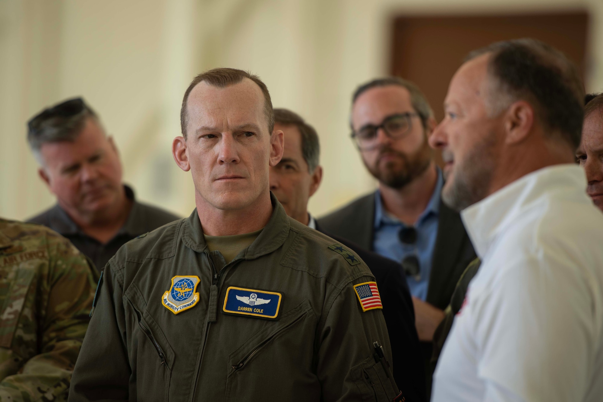 A close up of an Airman's face while a civilian is giving a presentation