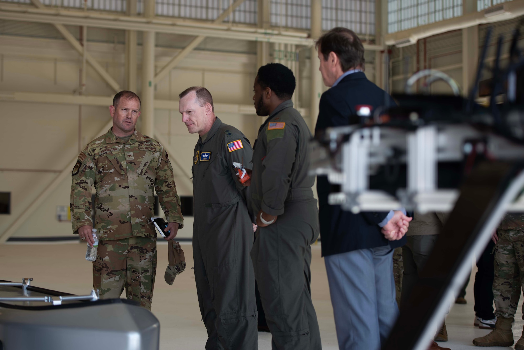 Airmen and civilians look at machinery.