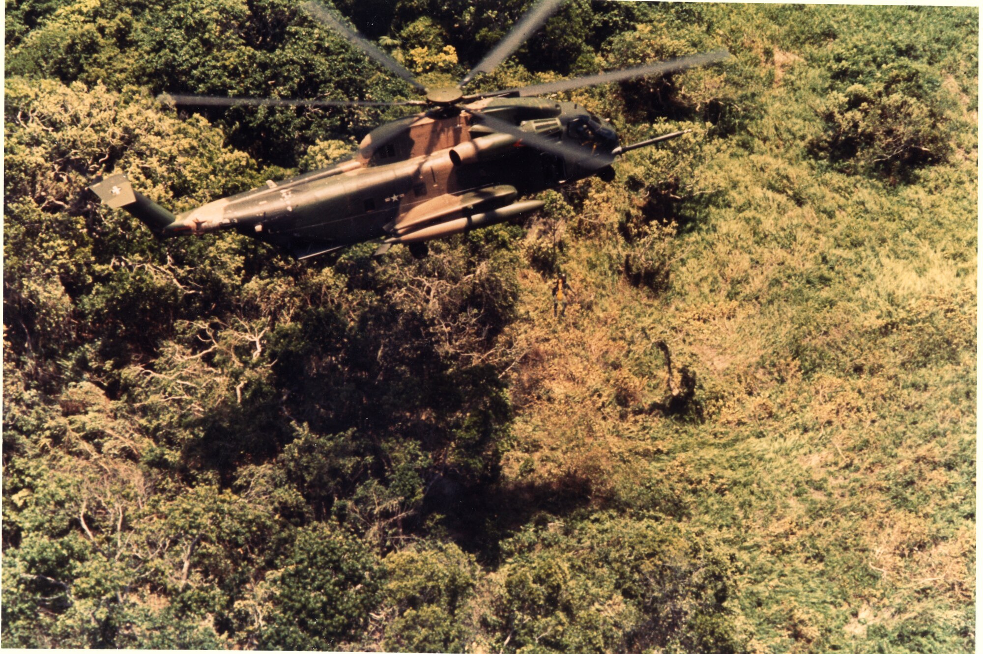 A PJ is lowered on a forest penetrator from a hovering HH-53 during a rescue mission in SEA, June 1970.