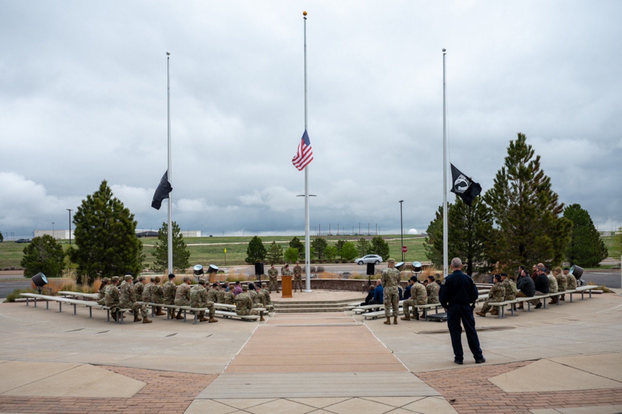members gathered in front of flag poles for a police week ceremony.