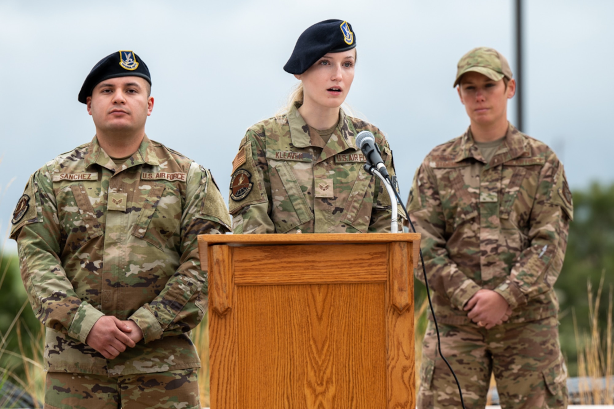 Security Forces members alongside a special agent speak at a podium.