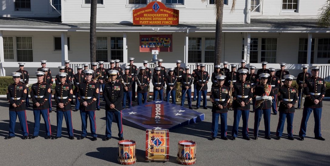 The 1st Marine Division Band, composed of 1 officer and 50 enlisted Marines pose in front of the Division Logo on Camp Pendleton, CA.