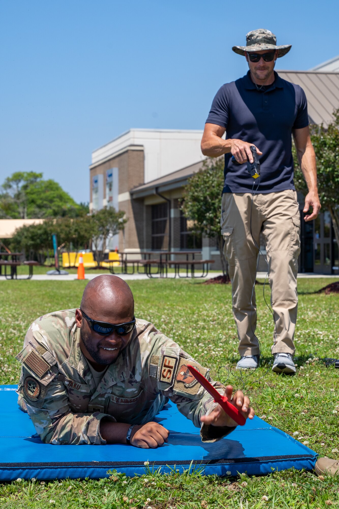 U.S. Air Force Tech. Sgt. Michael Taku, 81st Security Forces Squadron bravo flight sergeant, drops a training knife while being tased by Justin Depew, 81st SFS training instructor, during a demonstration for National Police Week at Keesler Air Force Base, Mississippi, May 16, 2023.