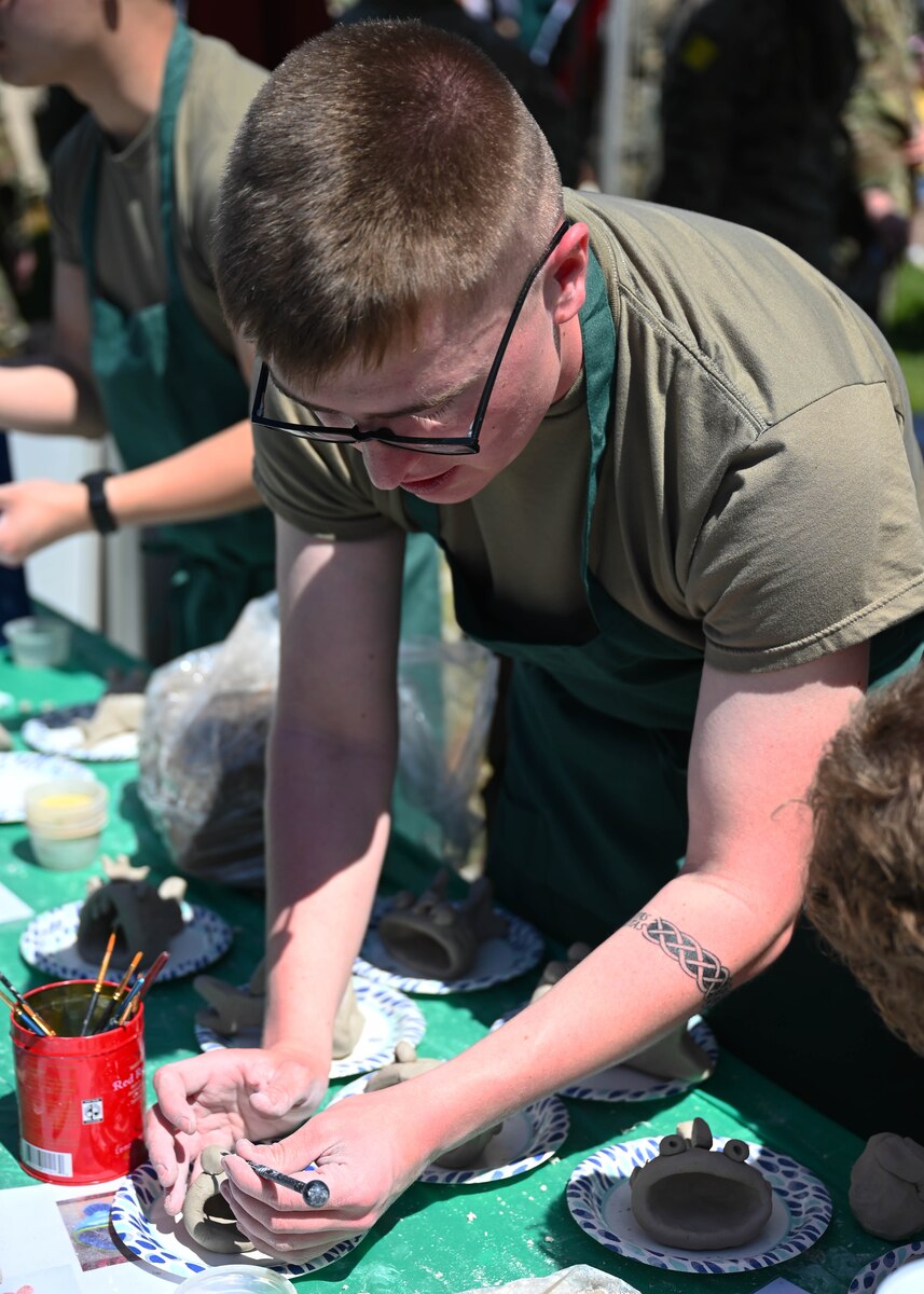 A student assigned to the 517th Training Squadron teaches visitors how to craft a frog from clay during Language Day at the Defense Language Institute Foreign Language Center, Calif., May 12, 2023. Students ran booths representing the culture they study at DLI. (U.S. Air Force photo by Airman 1st Class Zach Heimbuch)