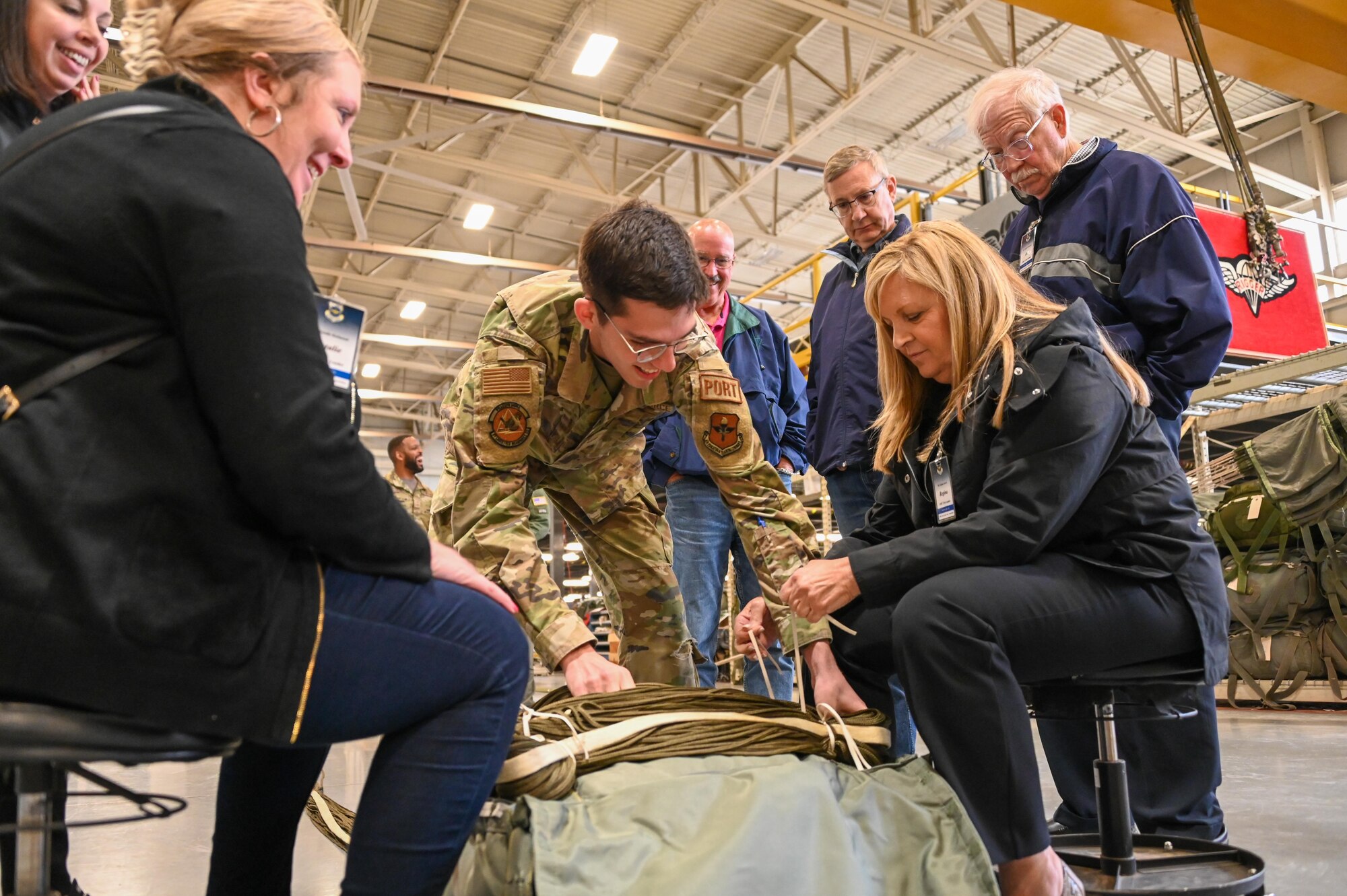U.S. Air Force Airman First Class Drake O'Neal, 97th Logistics Readiness Squadron unilateral aircrew training rigging member, shows Air Mobility Command civic leaders how to pack a cargo parachute at Altus Air Force Base, Oklahoma, April 27, 2023. The 97th LRS ‘Port Dawgs’ pack parachutes and create pallets to support the mobility mission at Altus AFB. (U.S. Air Force photo by Senior Airman Kayla Christenson)