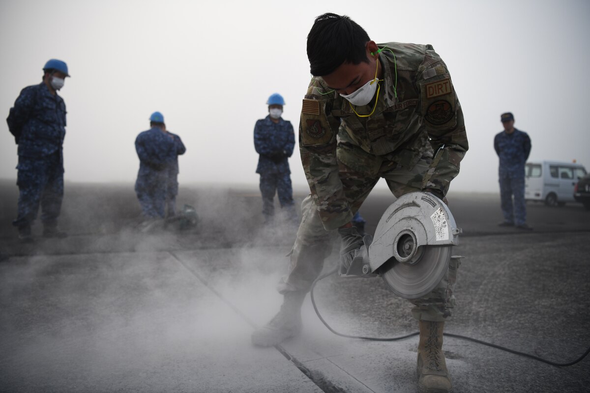 Airman 1st Class John Olarte, 374th Civil Engineering Squadron pavement and heavy equipment journeyman, cuts concrete to perform a spall repair at Kanoya Air Base, Japan, May 15, 2023. A four-man team from Yokota Air Base traveled to Kanoya to teach Japan Maritime Self-Defense Force engineers how to complete a spall repair. (U.S. Air Force photo by Staff Sgt. Spencer Tobler)