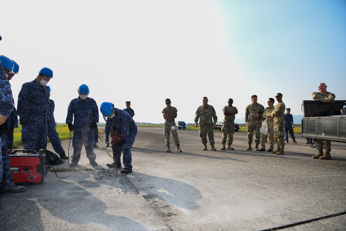 Members of the Japan Maritime Self-Defense Force complete a spall repair in front of U.S. Air Force personnel at Kanoya Air Base, Japan, May 15, 2023. Spall repairs are an efficient way to keep airfields serviceable by removing and replacing damaged parts of concrete slabs. (U.S. Air Force photo by Staff Sgt. Spencer Tobler)