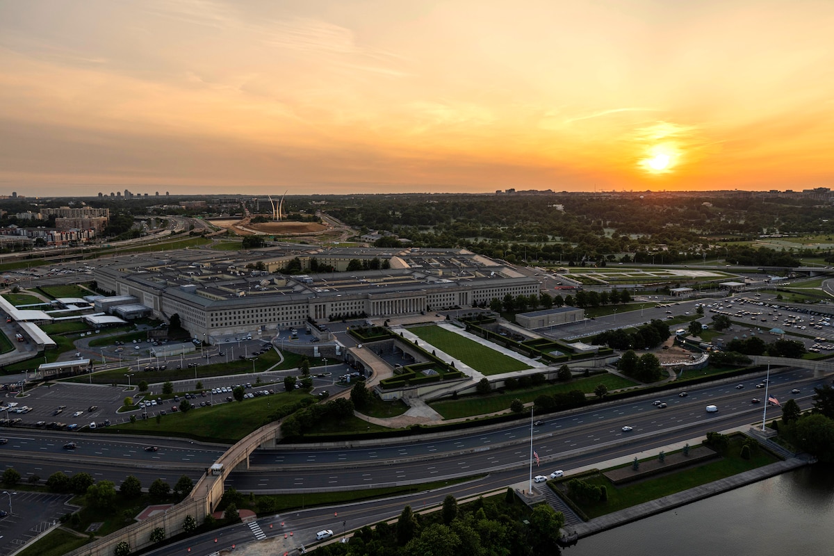 An aerial view of the Pentagon and surrounding area, with an orange sky as backdrop.