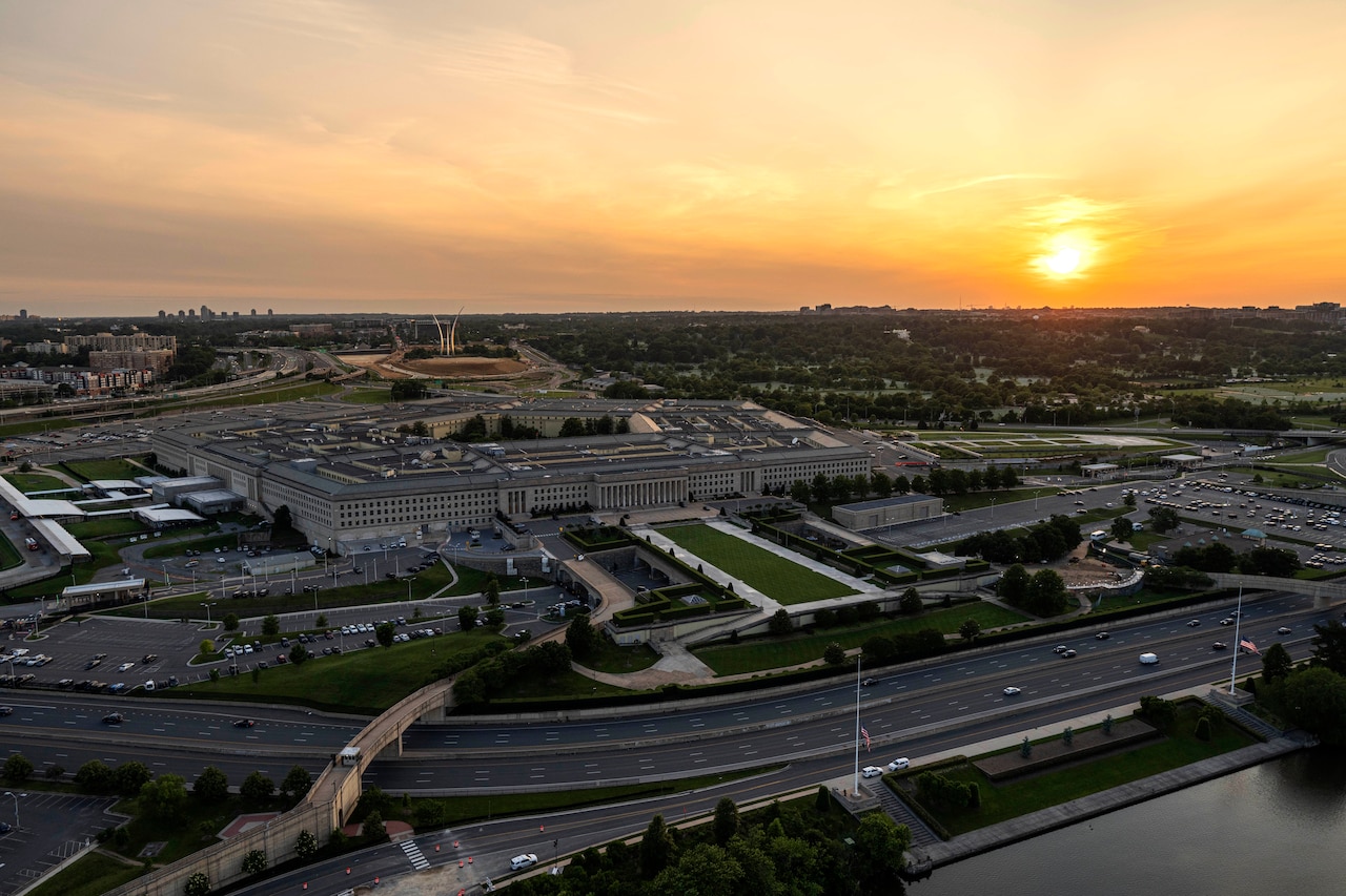 An aerial view of the Pentagon and surrounding area, with an orange sky as backdrop.