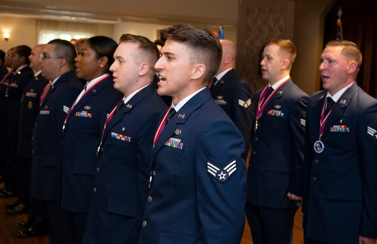 A group of Airmen stand in formation and are speaking in unison.