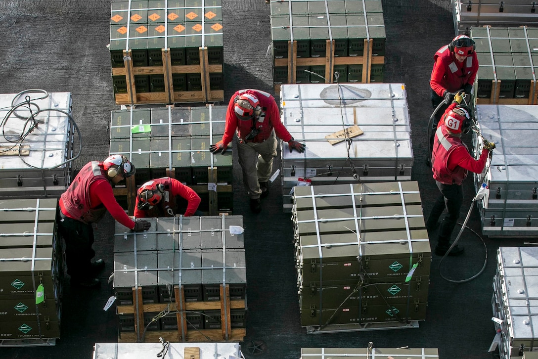 Aerial view of sailors handling supplies on the flight deck of a ship.