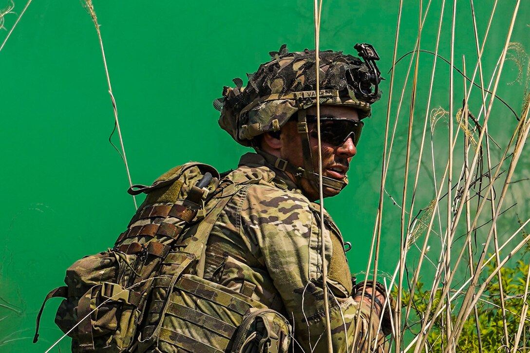 A soldier stands in front of a plume of green smoke.