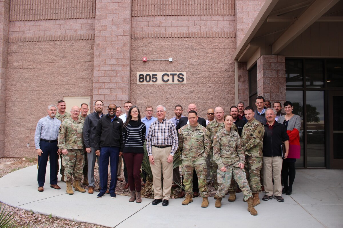 photo of a group of uniformed U.S. military members and civilians stand outside of building.  The building has a sign that says "805 CTS"