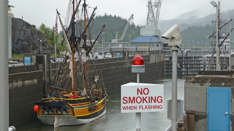 A pirate ship sits in the water in a large concrete basin on a cloudy day.