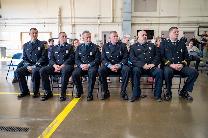 Six Wright-Patt firefighters sit and listen to a speech.