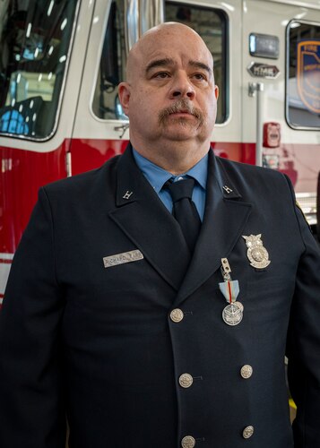 Capt. Richard Tarr stands at attention in front of a fire truck.