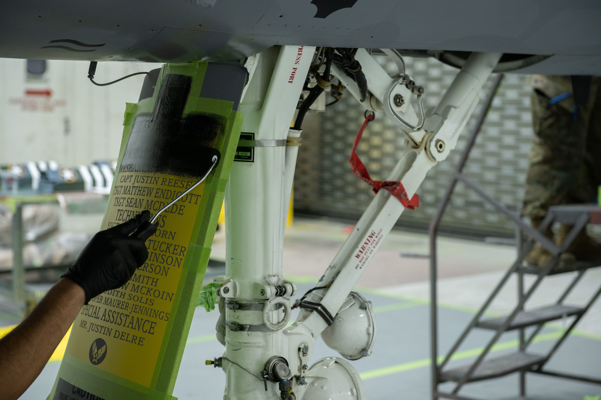 Airmen assigned to the 4th Equipment Maintenance Squadron fabrications flight paint a stencil with the names of the Airmen who painted the flagship jet at Seymour Johnson Air Force Base, North Carolina, April 12, 2023. The flagship jet features a portrait of Donald Blakeslee to honor an important member of the 4th Fighter Wing heritage. (U.S. Air Force photo by Airman 1st Class Rebecca Sirimarco-Lang)