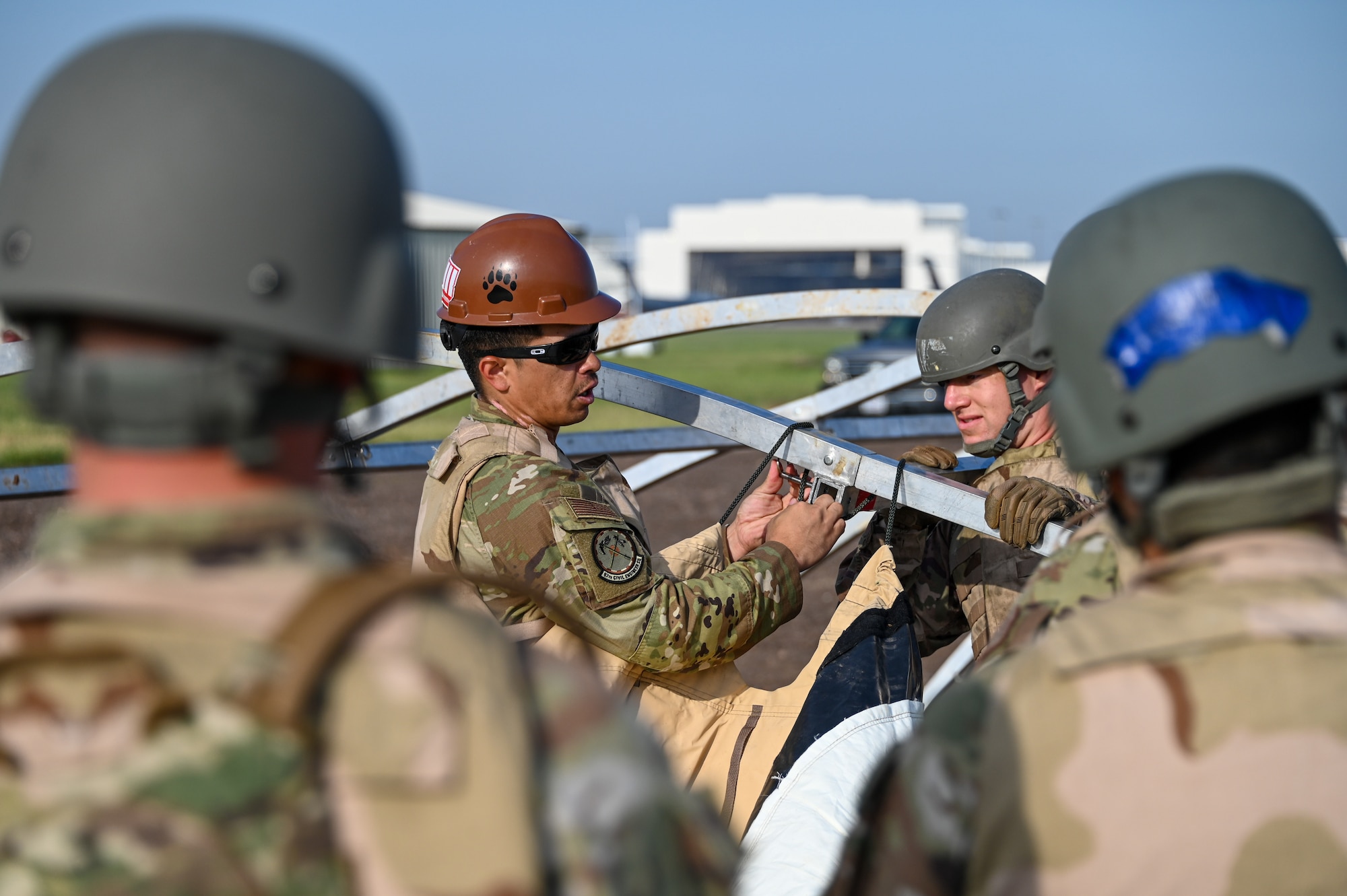 U.S. Air Force Staff Sgt. Brandan Pita, 97th Civil Engineering Squadron (CES) structures non-commissioned officer in charge, shows Airmen from 97th CES how to build a tent at Altus Air Force Base, Oklahoma, May 10, 2023. Large tents may be used in deployed environments to protect people and equipment from the outside elements. (U.S. Air Force photo by Senior Airman Kayla Christenson)