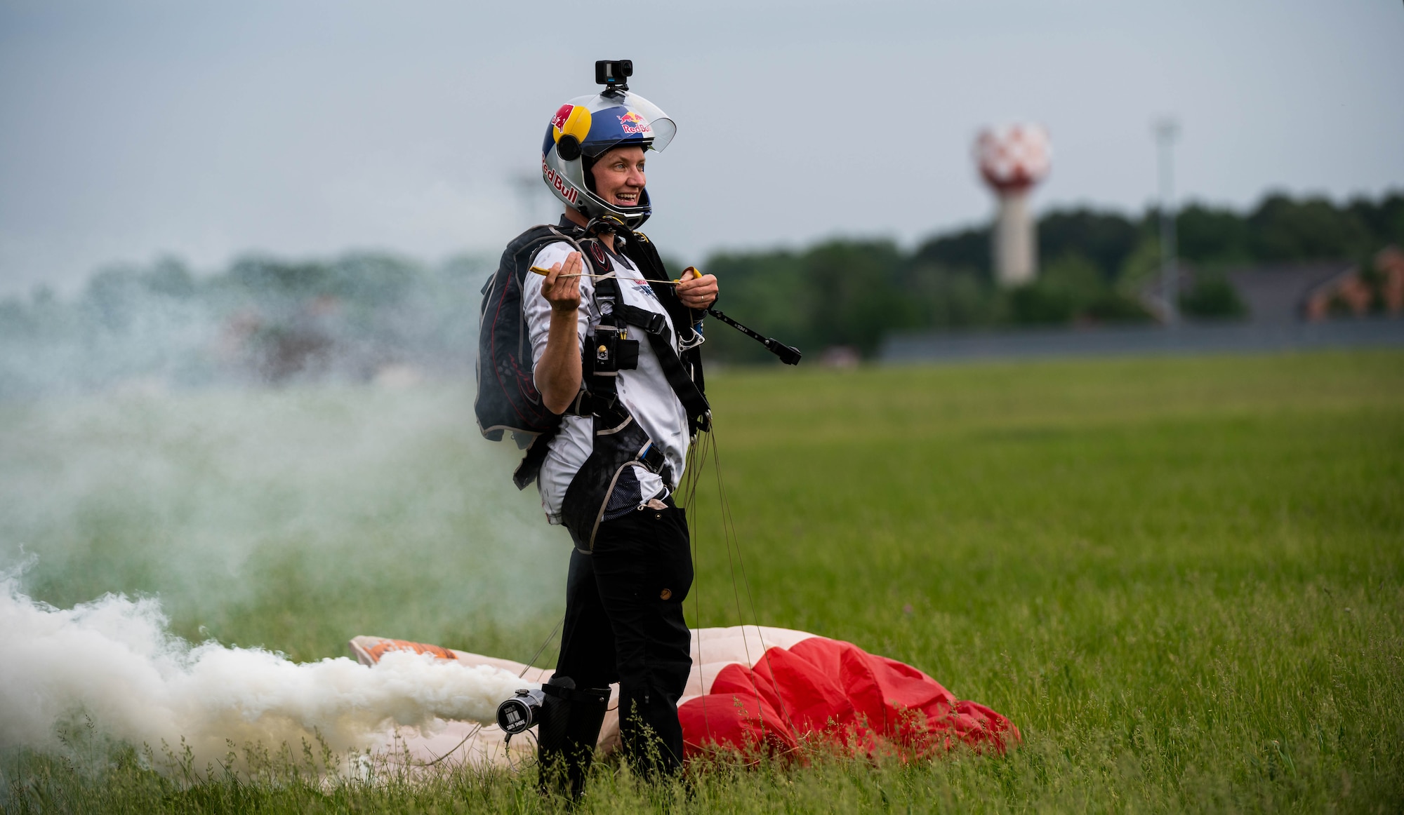 Skydiver with parachute poses for photo in field