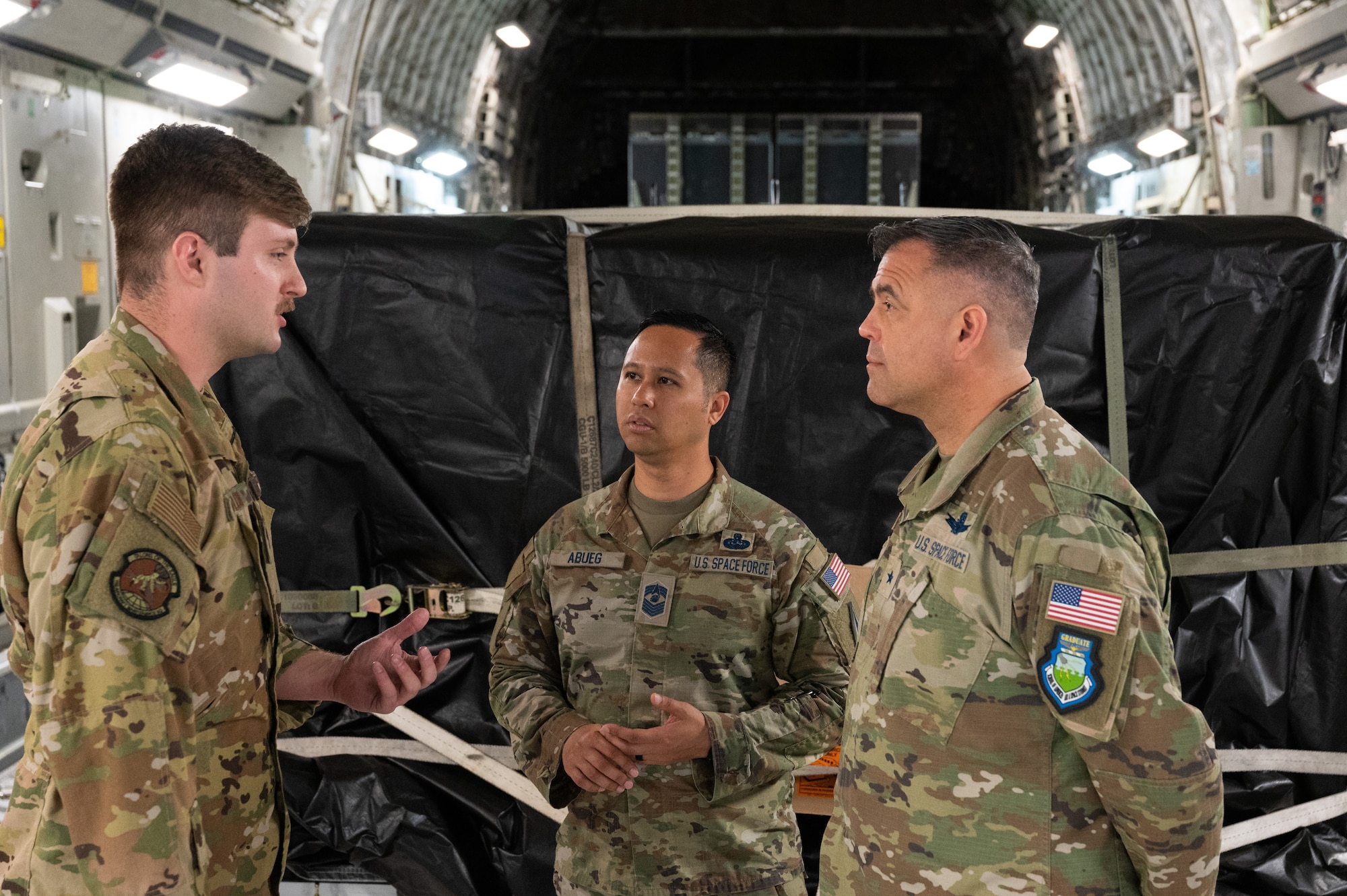 Staff Sgt. Kyle Wilson, 736th Aircraft Maintenance Squadron flying crew chief out of Dover Air Force Base, Delaware, speaks with Brig. Gen. Anthony Mastalir, U.S. Space Force-Indo-Pacific commander, and Chief Master Sgt. Leomel I. Abueg, U.S. Space Force-Indo-Pacific Component-Field Command Senior Enlisted Leader, Joint Base Pearl Harbor-Hickam, Hawaii, May 9, 2023. The U.S. Space Force announced the delivery the second of two Space Domain Awareness sensors to Japan that will be hosted on Japanese satellites to build SDA capacity and resiliency, in support of a US-Japan cooperative effort called Quasi-Zenith Satellite System Hosted Payload. (U.S. Air Force photo by Tech. Sgt. Hailey Haux)