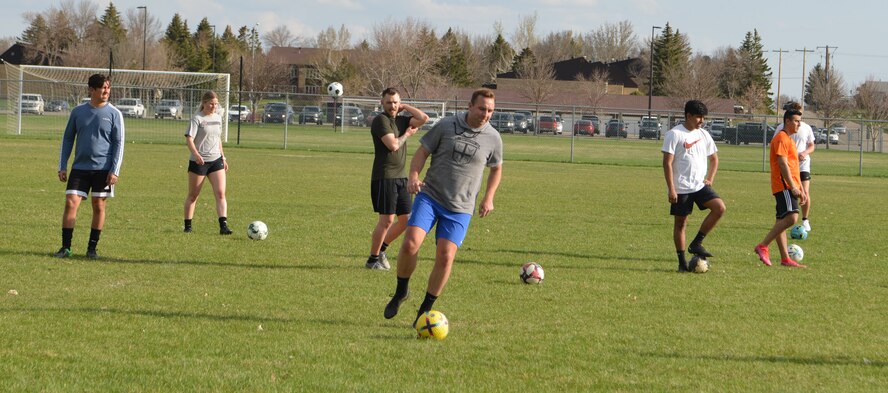 U.S. Air Force Capt. Micheal Thrasher, 5th Security Forces Squadron director of operations and Air Force Soccer Club coach, sprints with the soccer ball at the Sertoma Sports Complex, Minot, North Dakota, May 10, 2023. Everyone warmed up before the practice officially started. (U.S. Air Force photo by Airman 1st Class Trust Tate)