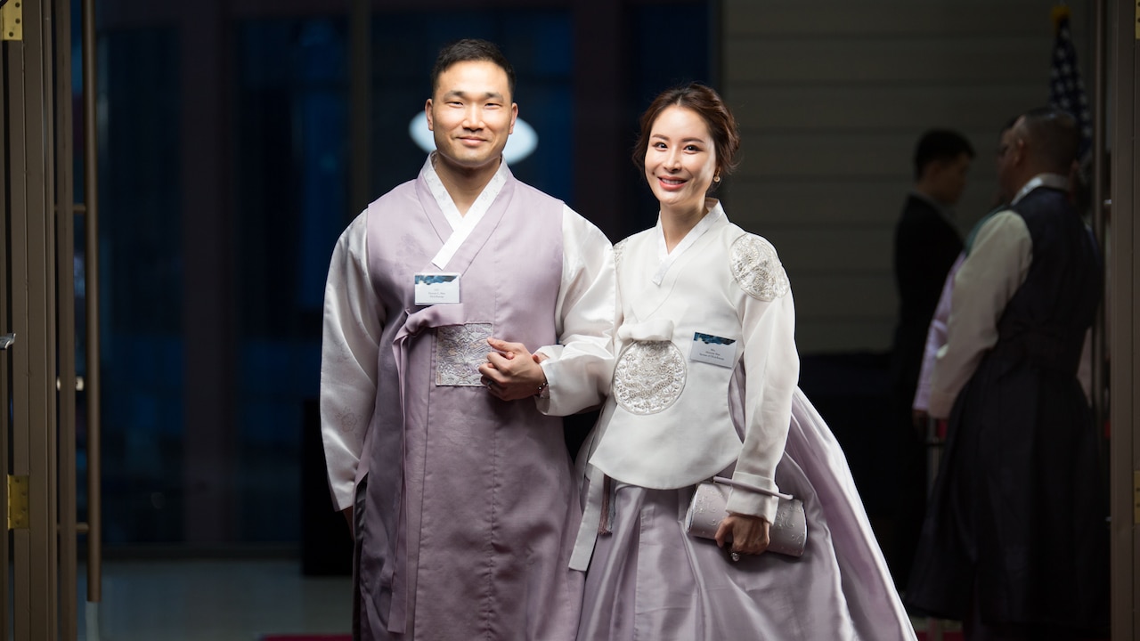 A man and woman hold hands while posing for a photo.