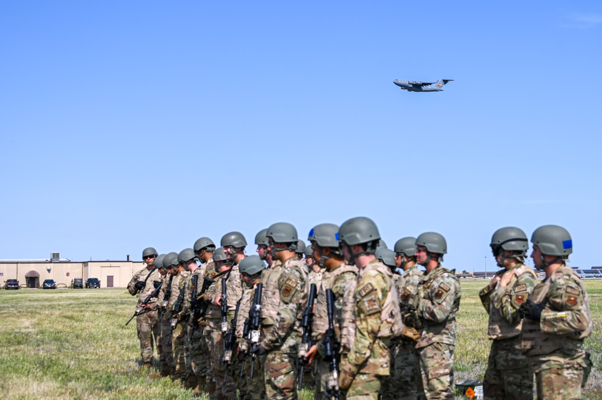 A C-17 Globemaster III takes off behind Airmen from the 97th Civil Engineering Squadron (CES) at Altus Air Force Base, Oklahoma, May 10, 2023. More than 50 Airmen from the 97th CES participated in a deployment training partnered with the 97th Security Forces Squadron. (U.S. Air Force photo by Senior Airman Kayla Christenson)
