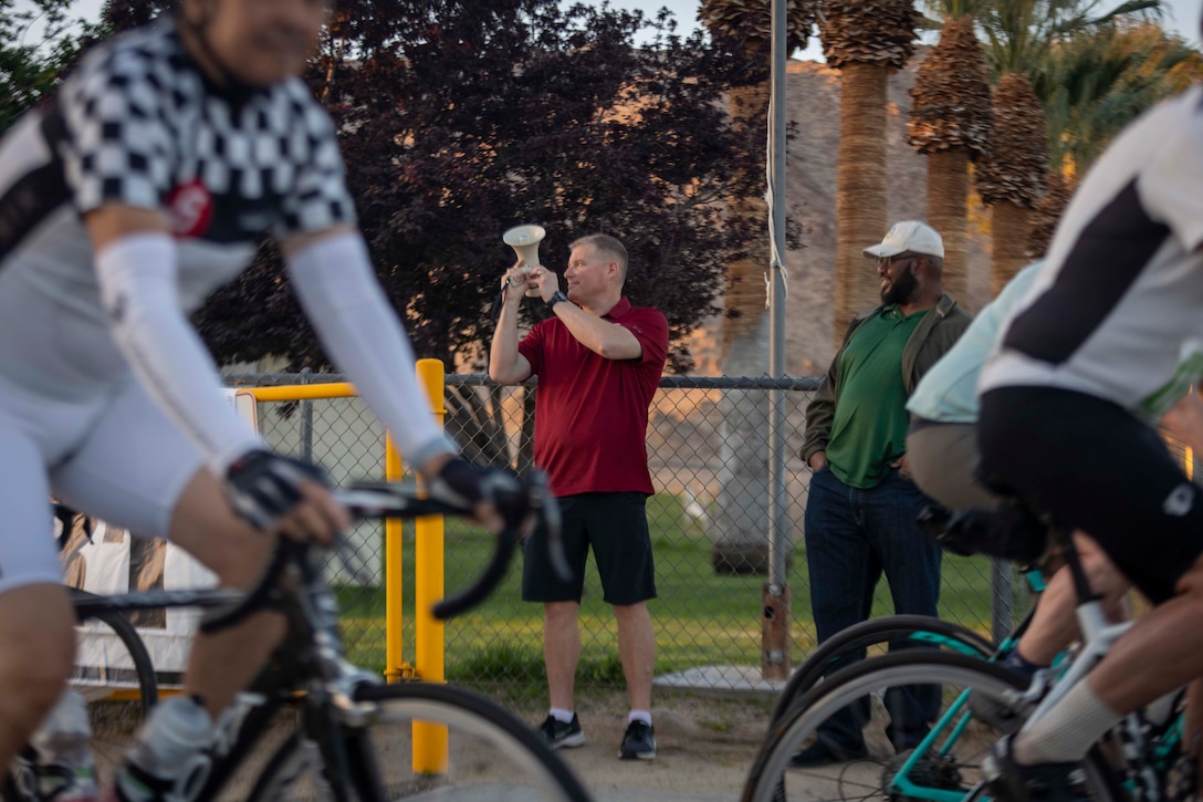 U.S. Marine Corps Col. Matthew Bain, G-4 Assistant Chief of Staff with Marine Air Ground Task Force Training Command, Marine Corps Air Ground Combat Center signals the start of the ride during the Joshua Tree (JT) 55 cycling event at Knotts Sky Park, Twentynine Palms, California, April 29, 2023. The JT 55 is a 55-mile cycling course that unites the Morongo Valley communities through sportsmanship and tradition. (U.S. Marine Corps photo by Cpl. Hunter Wagner)