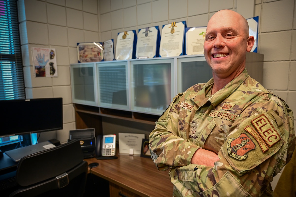 U.S. Air Force Master Sgt. Bryan Fletcher, 202nd RED HORSE Squadron recruiter, poses before a line of awards in his office located at Camp Blanding Joint Training Center in Starke, Florida, May 12, 2023. Fletcher was named the 2022 Air National Guard Top Geographically Separated Unit Advanced Recruiter by achieving a new enlistment contract rate of 164% of his annual goal. He was honored at the Air Force's annual Operation Blue Suit Arrival Ceremony held in March 2023 at Joint Base San Antonio-Randolph, Texas. (U.S. Air National Guard photo by Tech Sgt. Chelsea Smith)