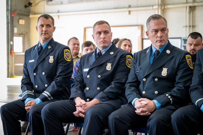 Capt. Greg Arnold, Firefighter Jeffrey Hoffman, and Firefighter/Paramedic Jared Spaeth sit and listen to a speech.