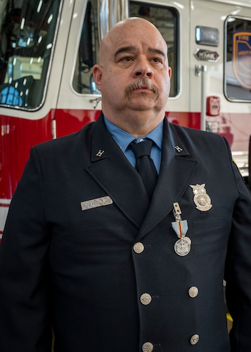 Capt. Richard Tarr stands at attention in front of a fire truck.