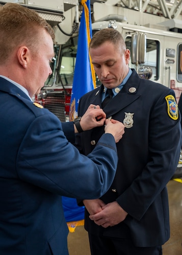 Maj. Nathan Thomsen pins a medal on Firefighter Jeffrey Hoffman.