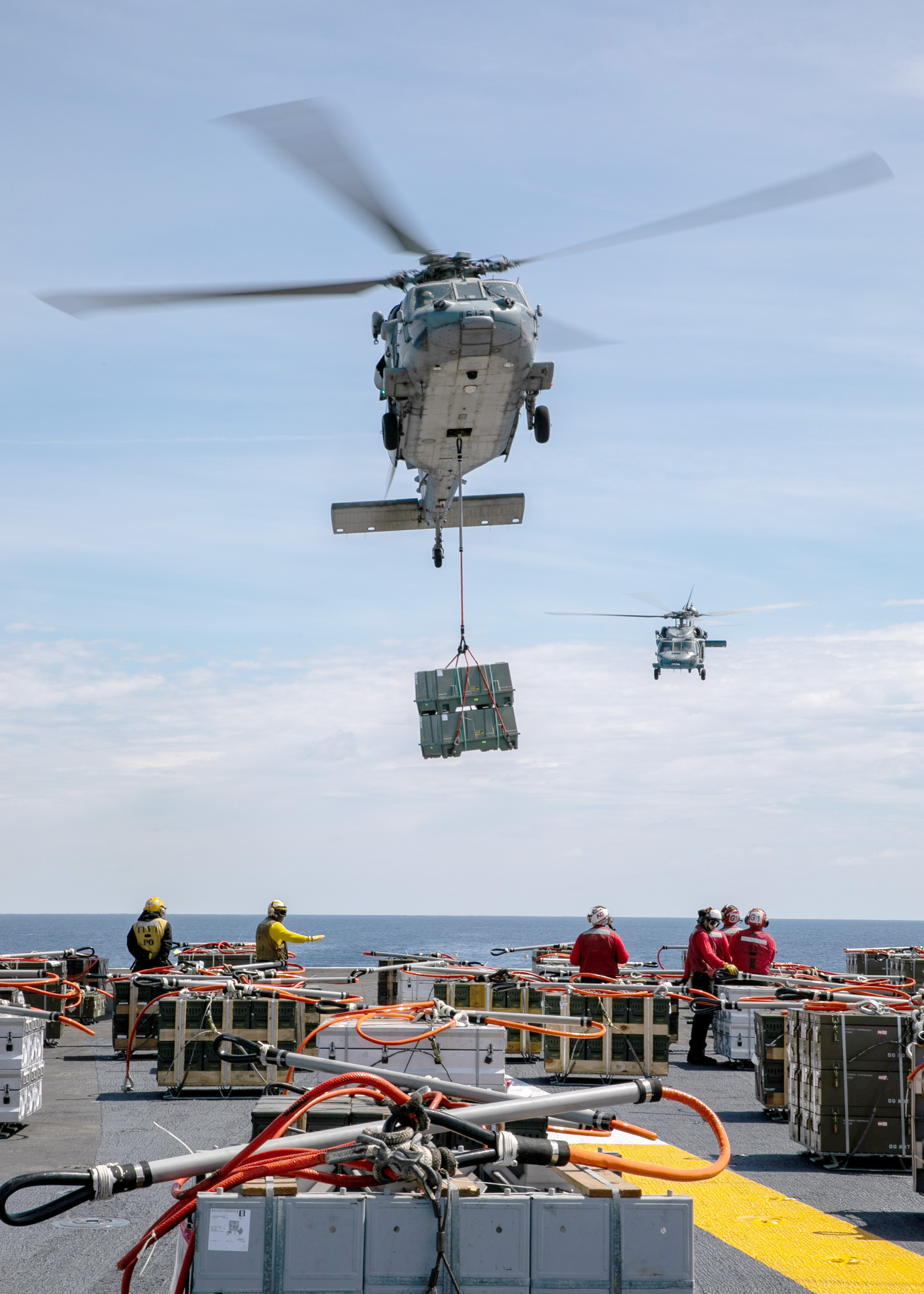 An MH-60S Sea Hawk helicopter attached to Helicopter Sea Combat Squadron (HSC) 5 retrieves ordnance from the flight deck of the Nimitz-class aircraft carrier USS George H.W. Bush (CVN 77) during an ordnance offload with the fast combat support ship USNS Supply (T-AOE 6).
